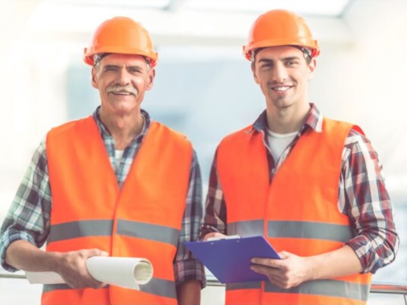 two workers holding a paper
